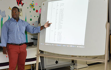 Dr Kinsy points to board as he teaches students